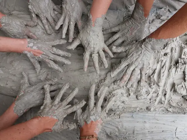 10 children's hands playing in gray fluffy paint.