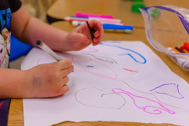 preschool child draws strokes on the paper with markers