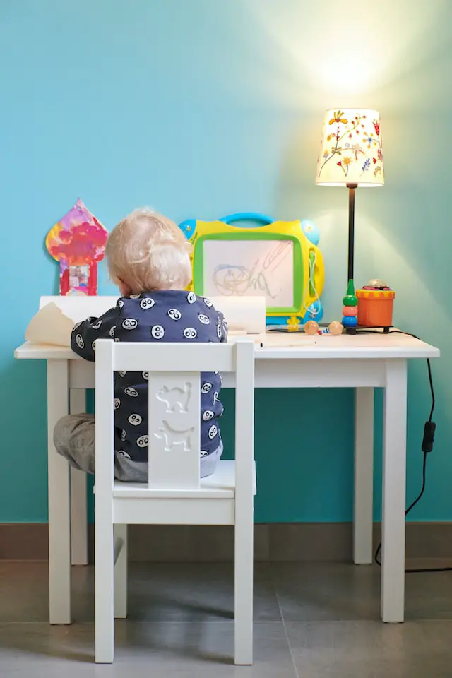preschooler sitting at a small desk drawing