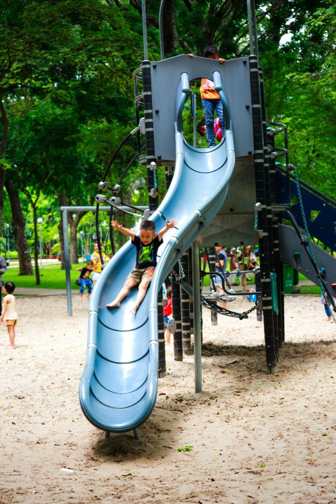 Child goes down a playground slide while engaging in gross motor play