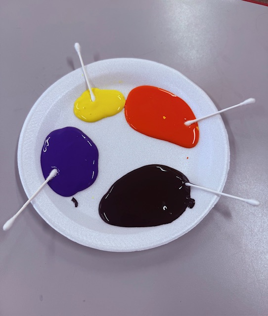 Q-tips with Halloween paint colors on a plate for fine motor dipping activity
